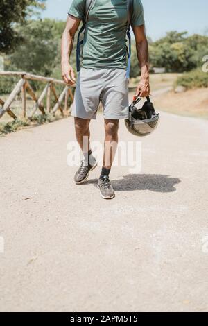 Junger Mann mit Helm, der im Park spazieren geht Stockfoto