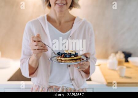 Nahaufnahme der Frau, die einen Teller mit Pfannkuchen und Obst hält Stockfoto