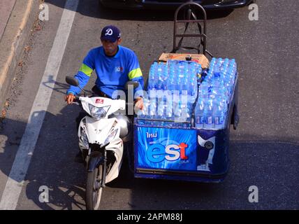 Ein Blick über den Kopf eines Mannes, der mit einem Motorrad in der Innenstadt von Bangkok, Thailand und Asien Wasserflaschen transportiert Stockfoto