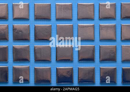 Ein karierter Hintergrund aus versiegelten, in Silberfolie flachen Würfeln, zerlegt und horizontal rechts und links geschnitten. Stockfoto