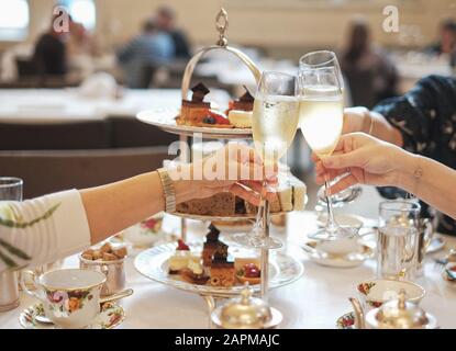Nachmittagstee High Tea mit Champagner, Kuchen, Sandwiches, Freunden und feinem china; ein fest mit Drinks Freundinnen gutes Essen großartige Atmosphäre Stockfoto