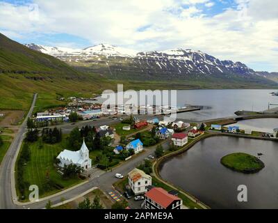 Luftbild der Gebäude, Wohnhäuser, Straßen und verschneiten Berge der Stadt im Sommer in der Nähe von Seydisfjordur, Island Stockfoto