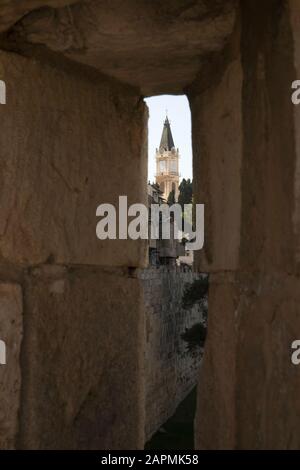 Uhrturm des Klosters Heiland im christlichen Viertel durch einen Pfeilerturm in der Umwallung der Altstadt von Jerusalem gesehen Stockfoto