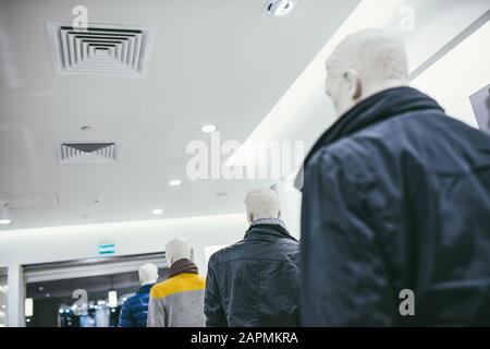 Mannequins stehen in einer Reihe im Laden und sind in verschiedene Kleidung gekleidet. Von unten nach oben zur Decke. Stockfoto