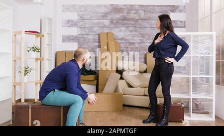 Junges Paar kommt mit Koffern in ihre neue Wohnung. Kartons im Hintergrund. Stockfoto