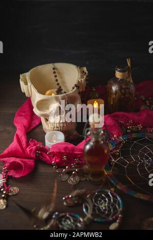 Gruselige Stillleben mit Tränken, Schädel, Mörtel, Vintage-Flaschen und Kerzen auf Hexentisch. Halloween oder esoterisches Konzept. Schwarze Magie und okkultes Objekt Stockfoto