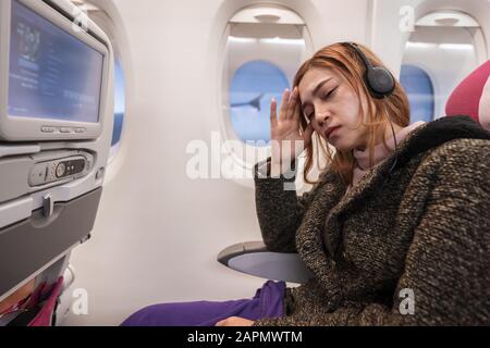 Frauen im Flugzeug leiden in einer Flugzeit an Airsick mit Stresskopfschmerzen. Stockfoto