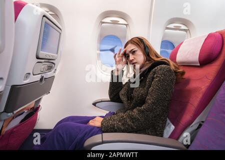 Frauen im Flugzeug leiden in einer Flugzeit an Airsick mit Stresskopfschmerzen. Stockfoto