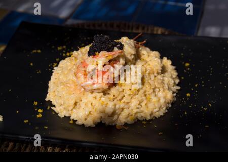 Risotto mit Meeresfrüchten auf schwarzem Teller. Stockfoto