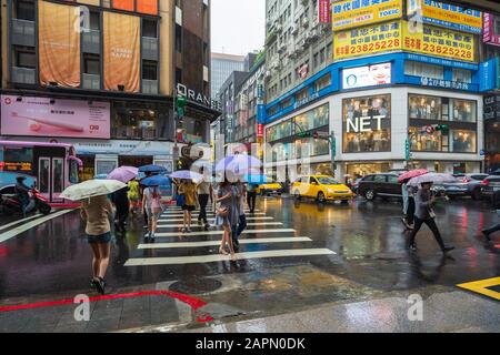 Taipeh, Taiwan - 11. Juni 2019: Menschen, die die Straße im Bezirk Ximen überqueren, mit fallendem Regen in Taipeh, Taiwan Stockfoto