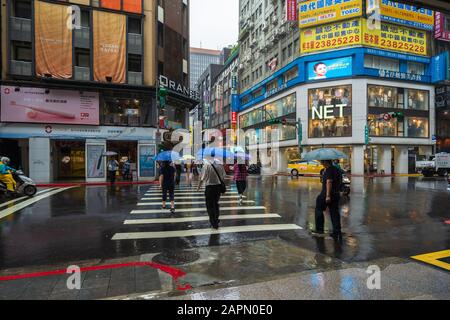 Taipeh, Taiwan - 11. Juni 2019: Menschen, die die Straße im Bezirk Ximen überqueren, mit fallendem Regen in Taipeh, Taiwan Stockfoto