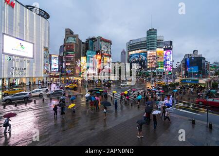 Taipeh, Taiwan - 8. Juni 2019: Verkehr und Menschen, die auf einem Querswalk mit fallendem Regen in Ximending in Taipeh, Taiwan, spazieren gehen. Ximending ist die berühmte Mode Stockfoto