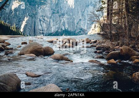 Fluss umgeben von Felsen und Grün unter dem Sonnenlicht in Das Yosemite Valley Stockfoto