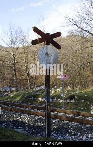 Voller Schuss eines alten Stoppschildes neben einer Eisenbahn Mit getrockneten blattlosen Bäumen im Hintergrund Stockfoto