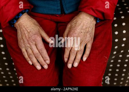 Nahaufnahme einer älteren chinesischen Frau, die mit Händen sitzt Auf den Knien Stockfoto