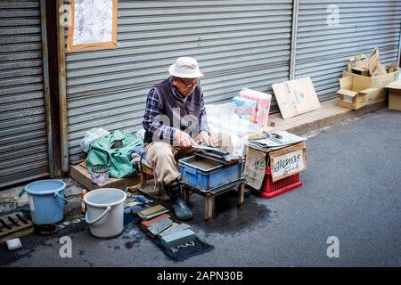 Ein Mann, der 2018 auf der Straße in Osaka, Japan, einen Messerschärfdienst anbietet. Stockfoto