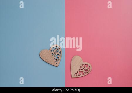 Zwei aus Holz geschnitzte Herzen auf pinkfarbenem und blauem Hintergrund mit Kopierraum. Hintergrundminimalismus zum Valentinstag, Muttertag, Geburt eines Kindes. Pos Stockfoto