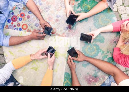Multirassische Gruppe von Freunden, die mobil süchtig sind - Über Wifi verbundene Personen in einer Tischbesprechung - Top View Hands Circle mit Mobiltelefonen - neue Trends und Stockfoto