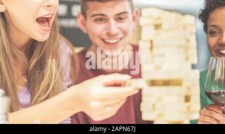 Eine Gruppe junger Freunde, die zu Hause Spaß am Boardspiel haben - Verschiedene Kulturleute lachen und genießen gemeinsam Zeit in der Jugendherberge - Freundschaft und y Stockfoto