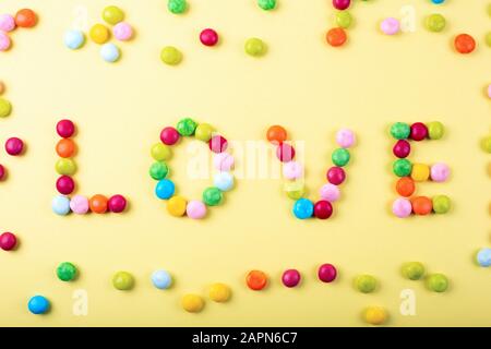 Gemischt mit bunten Süßigkeiten auf gelbem Hintergrund. Liebe Note Stockfoto