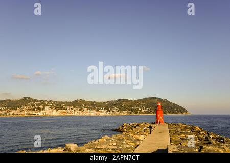 Seescape mit dem roten Leuchtturm von Porto Maurizio und der Küste mit dem Capo Berta kap im Hintergrund an einem sonnigen Tag, Imperia, Ligurien, Italien Stockfoto