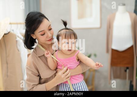 Zusammen zu arbeiten. Junge schöne Designer in der Nähe von Ihrem Baby Mädchen an ihrem Arbeitsplatz Stockfoto