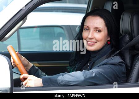 Fröhliche und lächelnde Seniorin im weißen Auto Stockfoto