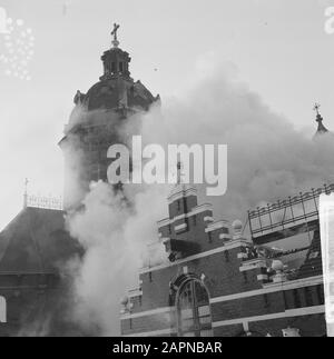 Feuer in der Lackfabrik Vettewinkel auf der Prins Hendrikkade in Amsterdam Rauch, der aus dem brennenden Gebäude stammt und die hinter der Kirche Sankt Nikolaus verbirgt Datum: 6. November 1965 Standort: Amsterdam, Noord-Holland Schlüsselwörter: Brände, Kirchenbauten, Rauch Stockfoto