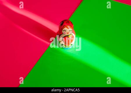 Stillleben - bunt bemalte Matryoshka (russische) Puppe auf neonrosa & grünem Hintergrund. Stockfoto