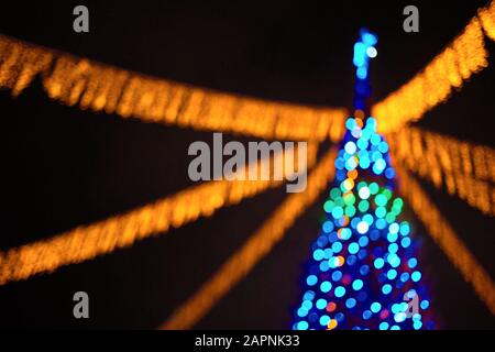 Weihnachtsbaum verschwommenes Bild mit bunten Lichtern und grindelig über dunklem Nachthintergrund mit Kopierbereich. Stockfoto