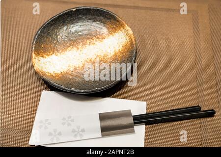 Keramikplatte auf Bambusmat, japanischer Stil. Essstäbchen. Stockfoto