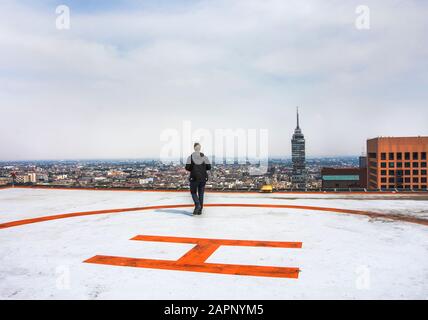 Männer, die auf dem Hubschrauberlandeplatz auf dem Dach des Gebäudes spazieren Stockfoto