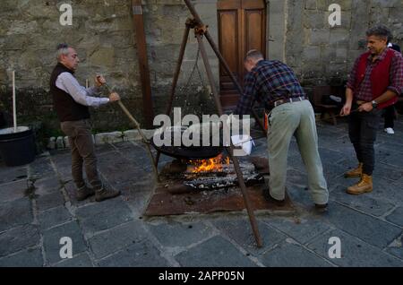 Die Einheimischen braten während des Oktoberfests, das die Kastanienernte feiert, bei einem offenen Feuer im toskanischen Bergdorf Gavinana Kastanien. Stockfoto