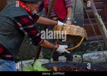 Die Einheimischen braten während des Oktoberfests, das die Kastanienernte feiert, bei einem offenen Feuer im toskanischen Bergdorf Gavinana Kastanien. Stockfoto