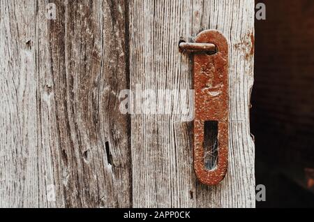 Alter rostiger Totschraubengriff an einer verwitterten Holztür. Stockfoto