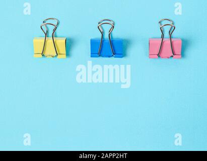 Bunte Binderclips auf blauem Papierhintergrund mit leerem Raum. Stockfoto