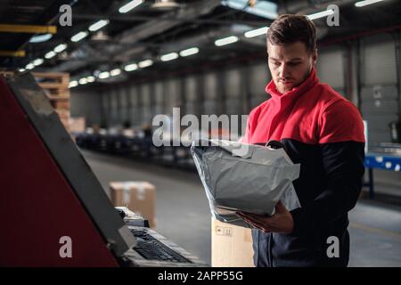 Kurier holt Paket auf einem Lager Stockfoto
