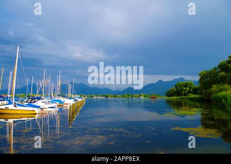 Ein kleiner Hafen am Chiemsee (Bayern, Deutschland) an einem ruhigen, schönen und sonnigen Sommertag. Mehrere Segelboote stehen in der Nähe eines Piers ab. Stockfoto