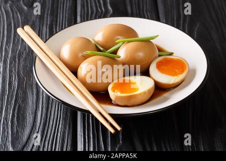 Köstlichen weich gekochten japanischen Eiern aus Nitramago in Sojamarinade mit grünen Zwiebeln in einem Teller auf dem Tisch. Horizontal Stockfoto