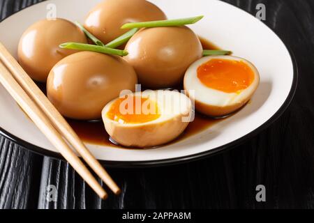 Weich gekochte Eier aus Niamago in Sojamarinade mit grünen Zwiebeln in einem Teller auf dem Tisch. Horizontal Stockfoto