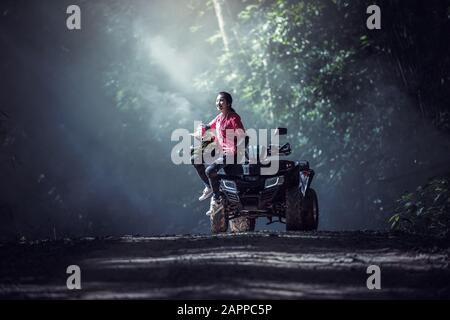 Elegante Frau, die im Wald Quadricycles ATV fährt Stockfoto