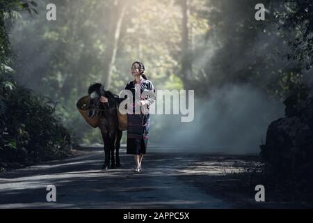 Asiatische Frau Arbeiter mit ihrem Esel in Wald Landschaft von Thailand Stockfoto