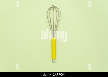 Neue Stahl-Schneebesen auf gren-Hintergrund reinigen. Rührer mit Eierbeater und Holzgriff zum Kochen Stockfoto