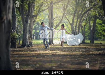 Brautpaar läuft und parkt und hält die Hände Stockfoto