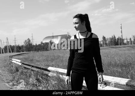 Pripyat, Ukraine, 20. Mai 2019. Traurige Frau mit dem Kernkraftwerk Tschornobyl im Hintergrund Stockfoto