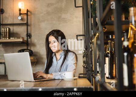 Portrait einer gutaussehenden geschweiften Geschäftsfrau, die im Café der Stadt sitzt und arbeitet, mit Laptop und Lächeln Stockfoto