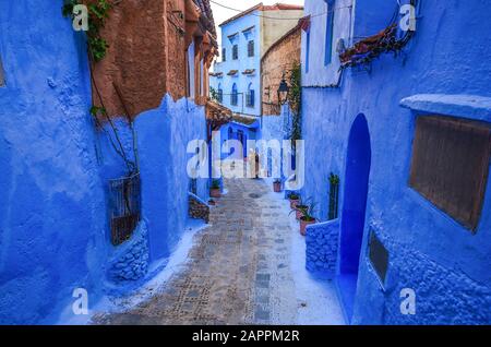 Frau in typisch marokkanischer Kleidung, die in der Stadt Chefchaouen eine Straße hinunterläuft. Stockfoto