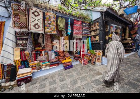 Mann in typisch marokkanischer Kleidung, der eine Straße in der Stadt Chefchaouen unterläuft. Stockfoto