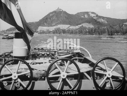 Holländischer Ruhm auf der Rheinschifffahrt, Reportage aus dem Schleppboot Damco 9: Westdeutschland. Drachenfels mit Ruine Burg Drachenfels über der Fahne und den Strandbremsen des Damco 9 Datum: 1. April 1955 Standort: Drachenfels, Deutschland, Westdeutschland Schlagwörter: Hügel, Burgen, Flüsse, Ruinen, Tümpel Stockfoto