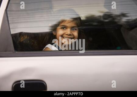 Kleines Mädchen, das durch das Autofenster schaut Stockfoto